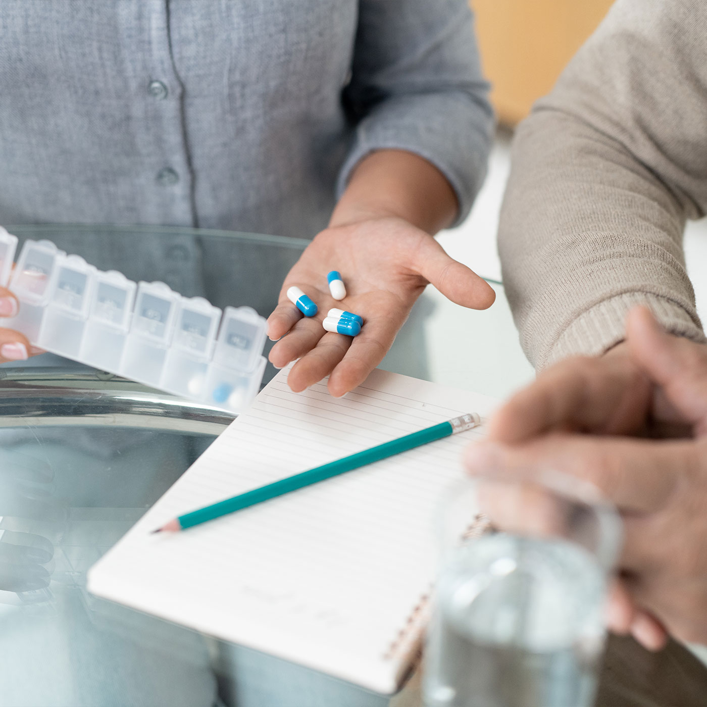 Tabletten in einem Wochendosierer neben einem Medikationsplan